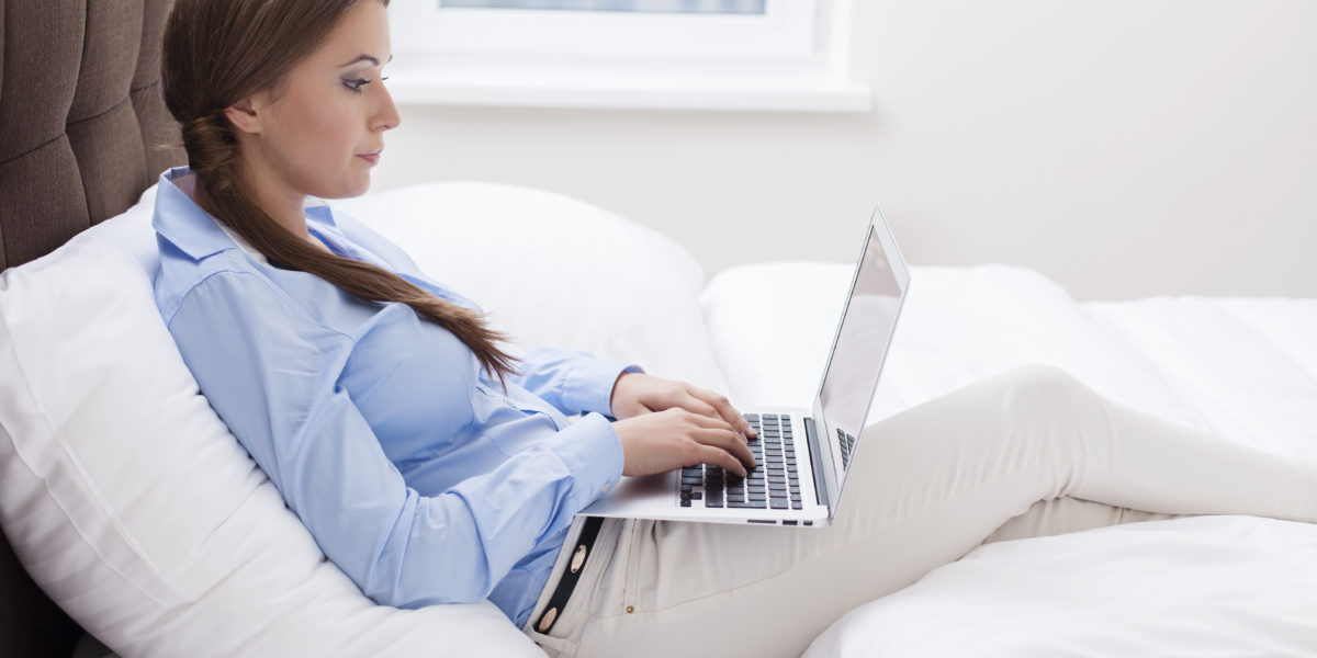 woman working on bed with laptop with work from home jobs
